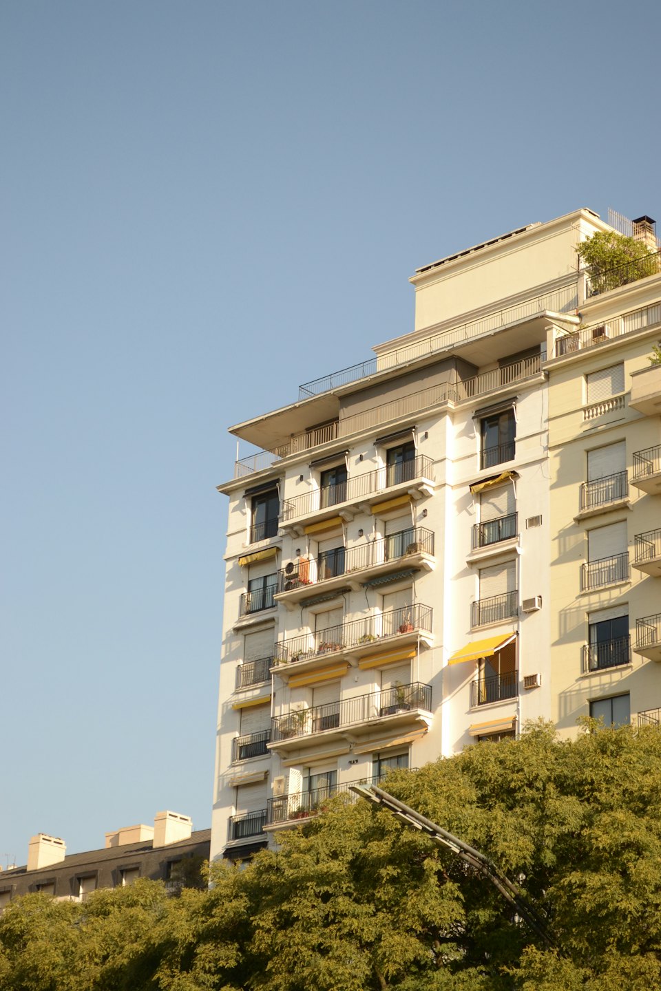 Modernes Wohnhaus mit gelben Markisen und schwarzen Balkongeländern.