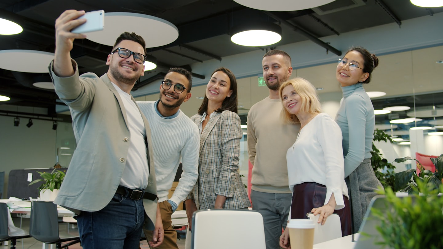 Teammitglieder machen ein Selfie in einem hellen, modernen Büro.