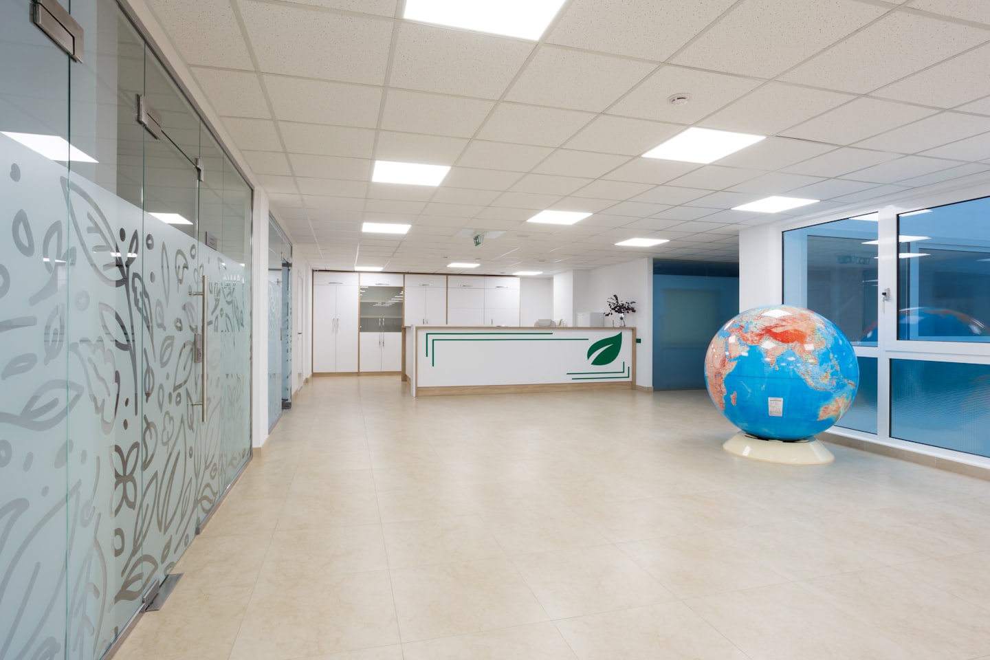 Moderne Bürorezeption mit Globus und Milchglasabtrennungen.